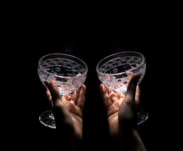 两只手拿着空酒杯在黑暗的背景下 — 图库照片