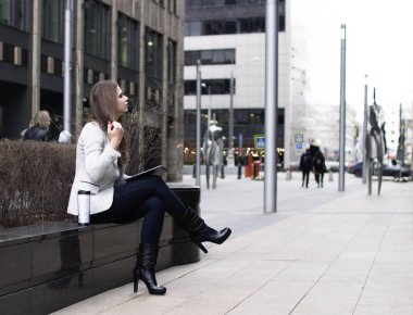 parlak bir ceket içinde bir kız oturuyor ve bir tablet tutuyor 