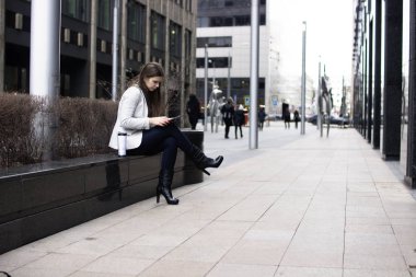 parlak bir ceket içinde bir kız oturuyor ve bir tablet tutuyor