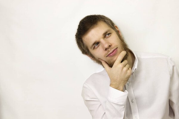 young man sits thoughtfully on a white background in a white shi