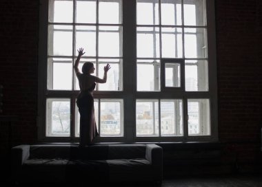 İpek giysili bir kadına bir pencere, bir kadın silueti, büyük bir pencere arka planda duruyor