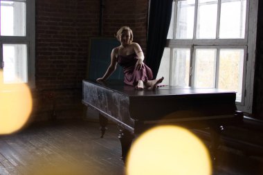 Pembe ipek elbiseli bir kadın uzağa arıyorsunuz piyanonun üzerinde oturur. Bu arka plan ve duvar tuğla