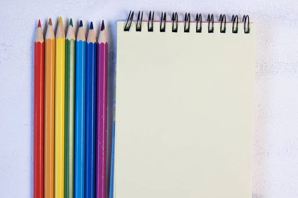 Lápiz de color con cuaderno sobre fondo blanco . — Foto de Stock