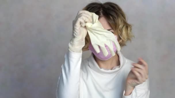 Młoda kobieta zdejmuje maskę medyczną i wyrzuca maskę i rękawiczki. Kobieta oddycha głęboko i uśmiecha się patrząc w kamerę. Kobieta cieszy się, że epidemia minęła 4k. — Wideo stockowe