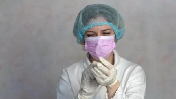 La joven se quita la máscara médica, el sombrero y los guantes médicos. La hembra respira profundamente y sonríe mirando a la cámara. Salud y concepto médico. Mujer se alegra de que la epidemia es más de 4k — Vídeos de Stock