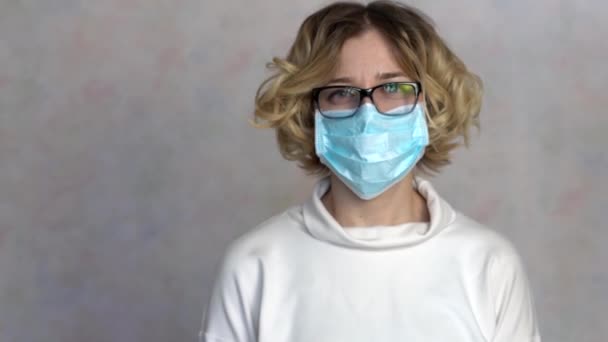 Young woman takes off medical mask. Female breathes deeply and smiling looking at camera. Health care and medical concept. Woman rejoices that the epidemic is over 4k — Stock Video