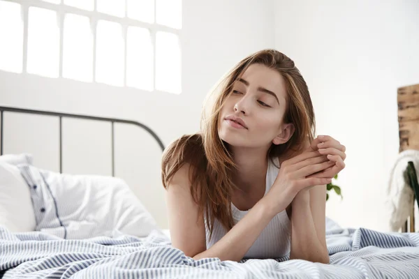Gondolkodó nő néz félre fekszik az ágyban — Stock Fotó
