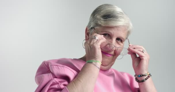 Пожилая женщина надевает очки и смотрит в камеру — стоковое видео