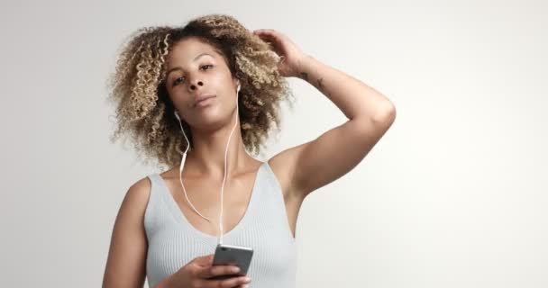 美混的血女人的典型黑人头发和雀斑耳机与智能手机的肖像 — 图库视频影像