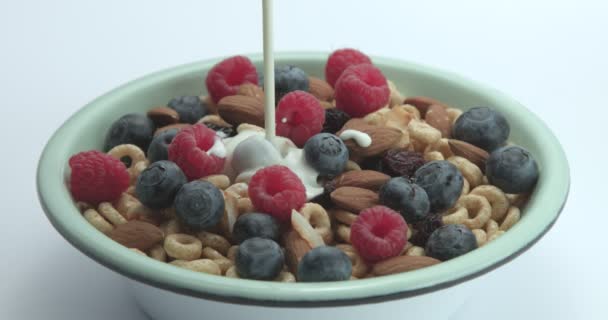 Melk gieten naar de bowl met cornflakes ringen met bessen en noten. — Stockvideo