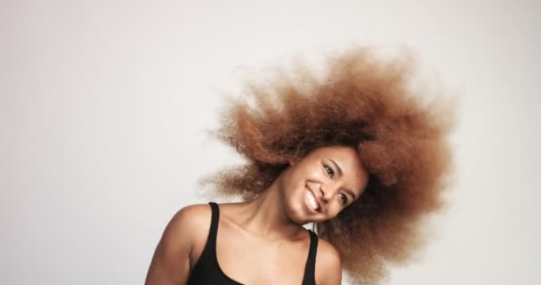 Черная женщина с огромными афро-волосами весело улыбается и танцует — стоковое видео