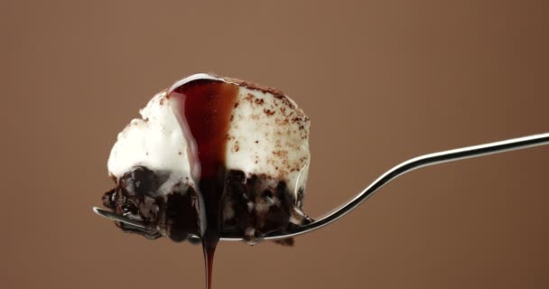 Trozo de pastel de chocolate en un tenedor con una crema blanca y una cubierta líquida — Vídeos de Stock