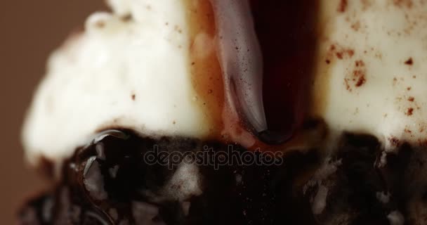 Piece of chocolate cake on a fork with a white cream and a liquid topping — Stock Video