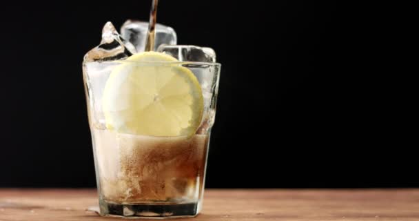 Vidro com cubos de gelo e lâmina de limão e cola. rom cola, bebida fresca, cubos de gelo e bolhas — Vídeo de Stock