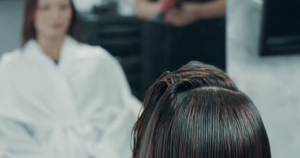 Woman sits in a professional salon behind the mirror and looks herself — Stock Video