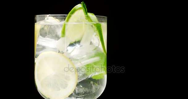Closeup of coctail. Mojito, tonik water with mint and lemon and lime and ice cubes — Stock Video