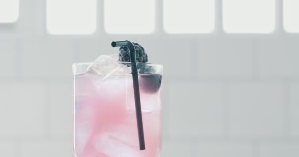 Pink lemonade or cocktail turning on its axis in daylight in bar — Stock video