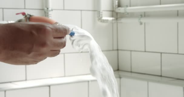 Mans lavar a mano una maquinilla de afeitar con agua en el baño soleado — Vídeo de stock