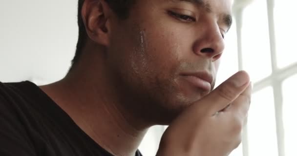 Человек смешанной расы касается его лица и бороды перед бритьем — стоковое видео