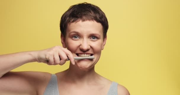 Смешной портрет женщины, чистящей зубы и смотрящей в камеру и с разных сторон — стоковое видео