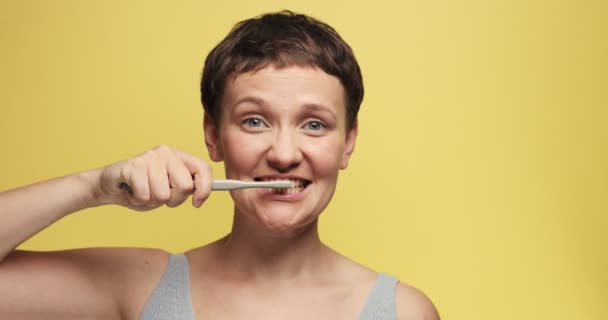 Grappige portret van vrouw reiniging van de tanden en kijken op camera en op verschillende kanten — Stockvideo