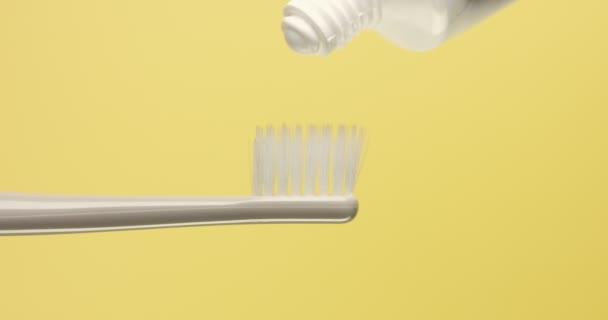 Close-up de escova de dentes e uma pasta de dente derramando sobre ele — Vídeo de Stock