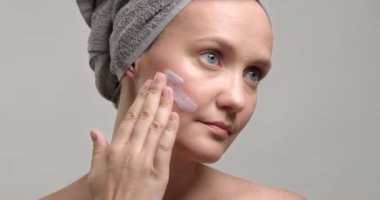 kadın bir krem yüzüne koyar.