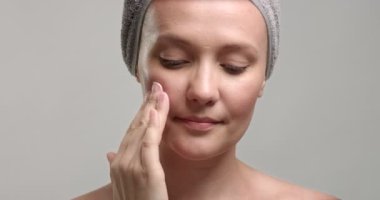 kadın bir krem yüzüne koyar.