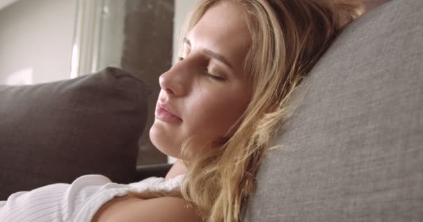 Молодая блондинка отдыхает на диване — стоковое видео
