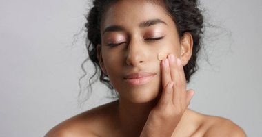 Studio bir temel üzerine yanak closeup ile Orta Doğu genç kadın cilt dokunmak