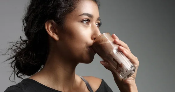 Laughing attractive Middle Eastern girl in relaxed black top drinking mocca, hot chocolate, caffee from a tall glass — Stock Photo, Image