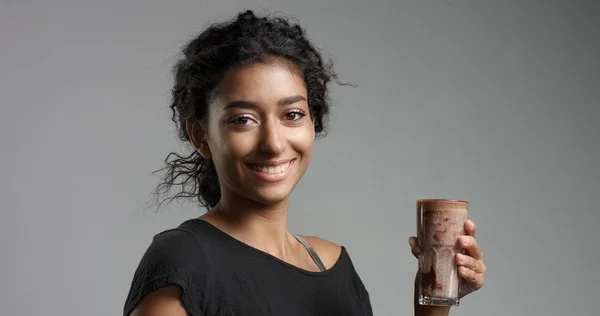 Laughing attractive Middle Eastern girl in relaxed black top drinking mocca, hot chocolate, caffee from a tall glass — Stock Photo, Image