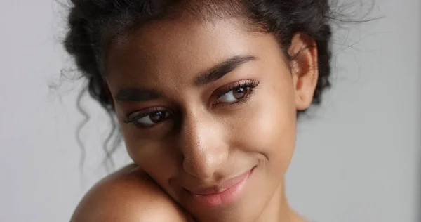 happy serene young woman with beautiful olive skin and curly hair ideal skin and brown eyes in studio