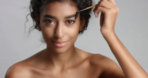 Pretty young girl with flawless skin brushing her eyebrow — Stock Photo, Image