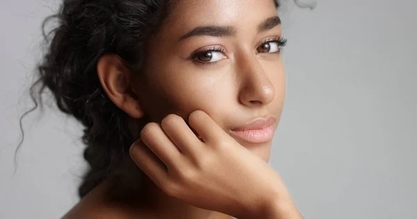 Gelukkig serene jongedame met mooie olijfolie huid en ideale huid van krullend haar en bruine ogen in studio — Stockfoto