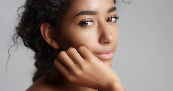 Happy serene young woman with beautiful olive skin and curly hair ideal skin and brown eyes