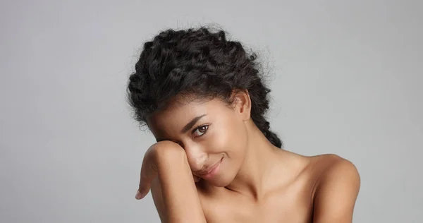 Felice giovane donna serena con bella pelle d'ulivo e capelli ricci pelle ideale e occhi marroni in studio — Foto Stock