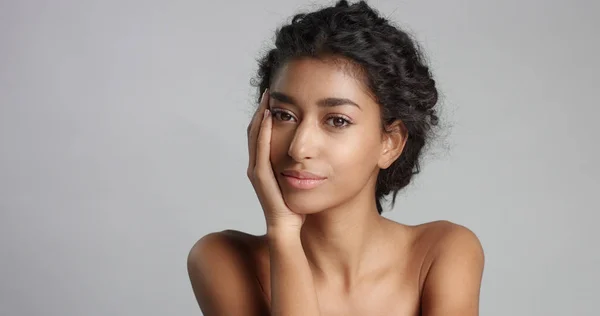 Gelukkig serene jongedame met mooie olijfolie huid en ideale huid van krullend haar en bruine ogen in studio — Stockfoto