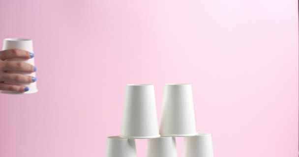 Torre hecha de tazas de papel blanco sobre fondo rosa — Vídeo de stock