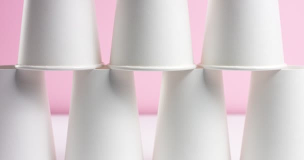 Torre hecha de tazas de papel blanco sobre fondo rosa — Vídeo de stock