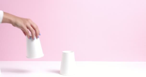 Tower made of white paper cups on pink background — Stock Video