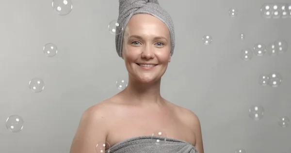 30-летняя женщина носит полотенце за ванной в окружении мыльных пузырей — стоковое фото
