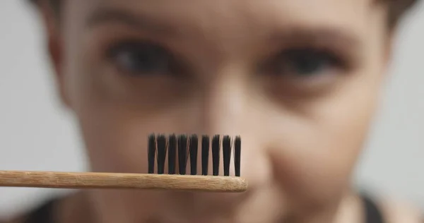 Wanita muda cantik menggosok giginya dengan pasta gigi hitam — Stok Foto