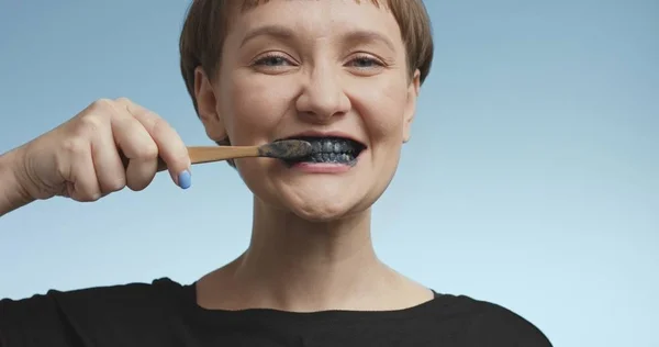 Mulher muito jovem escovando os dentes com pasta de dentes preta — Fotografia de Stock