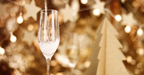 Champagne versato in un bicchiere con decorazioni natalizie — Foto Stock