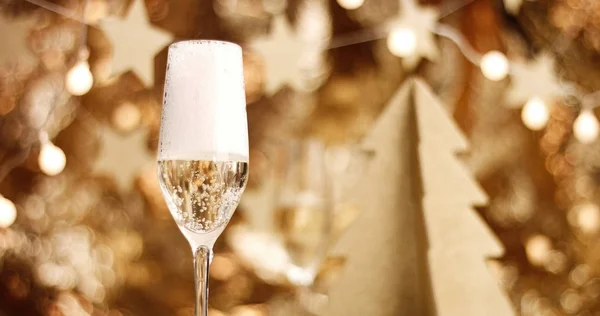 Champanhe derramado em um copo com decorações de Natal — Fotografia de Stock