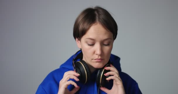 Hermosa mujer con capucha azul poniéndose auriculares — Vídeos de Stock