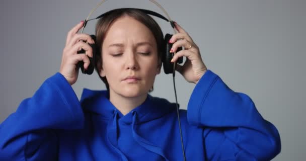 Hermosa mujer con capucha azul poniéndose auriculares — Vídeo de stock