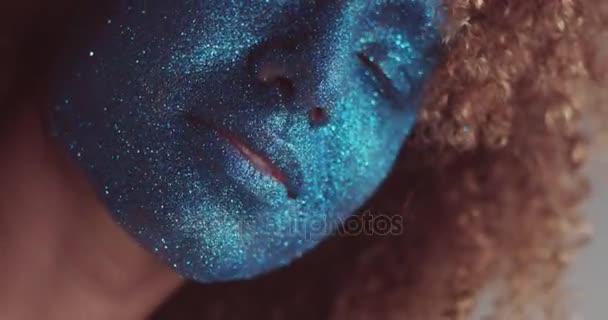 Mujer negra con cabello rubio y maquillaje de cara de brillo azul — Vídeo de stock