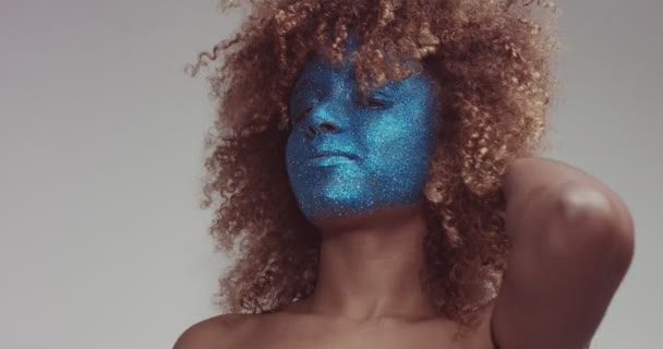 Schwarze Frau mit blonden Haaren und blauem Glitzergesicht — Stockvideo